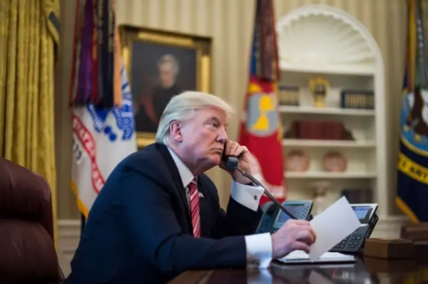 Трамп із телефонною трубкою біля вуха за столом у Овальному кабінеті