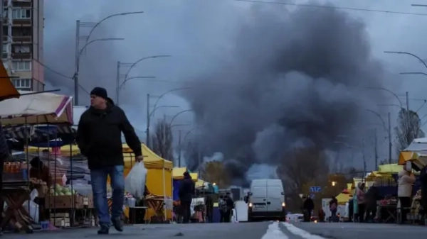 Автор фото, Reuters Чоловік ходить по ринку, поки на місці ракетного удару горить вогонь