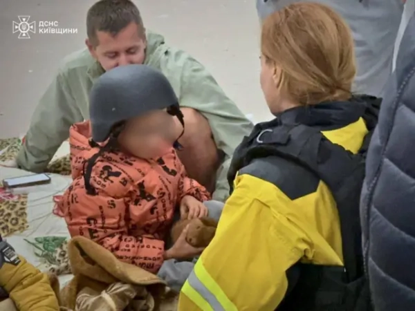 Автор фото, Thomas Peter via Reuters Рятувальники допомагають дитині після нічної атаки на Київ