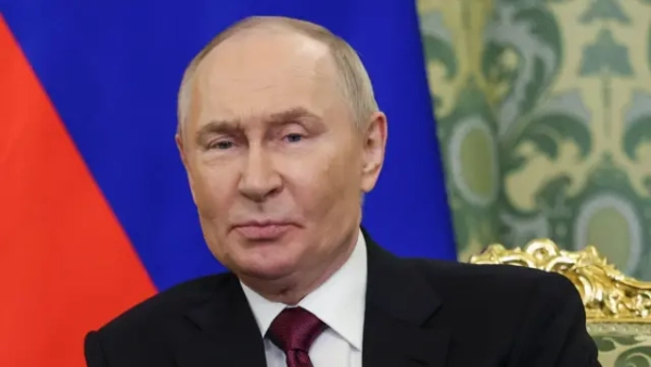 Президент Росії Володимир Путін сидить на стільці на тлі російського прапора