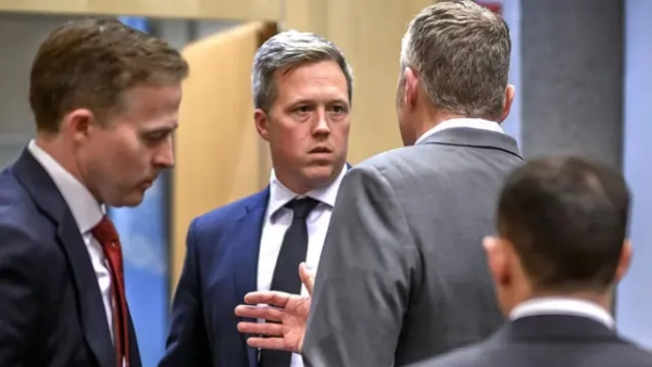 Дрісколл у костюмі стоїть поруч з іншими чоловіками у костюмах 